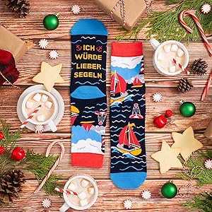Decorative holiday socks with sailing ship design displayed among Christmas decorations, pine branches, candy canes, and mugs of hot cocoa.