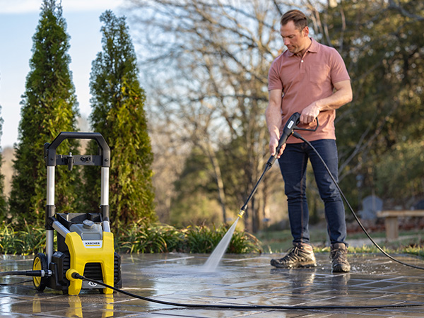 A person cleaning a stone patio using a pressure washer