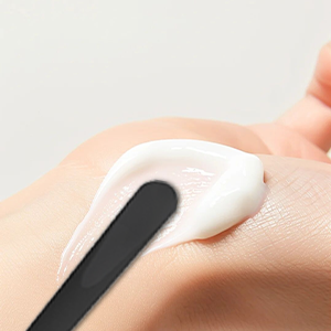 Close-up of white handheld device or tool with black accent being used on skin surface.