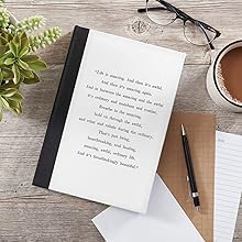 black and white journal notebook on a desk with a pen coffee mug set of eyeglasses and a plant 