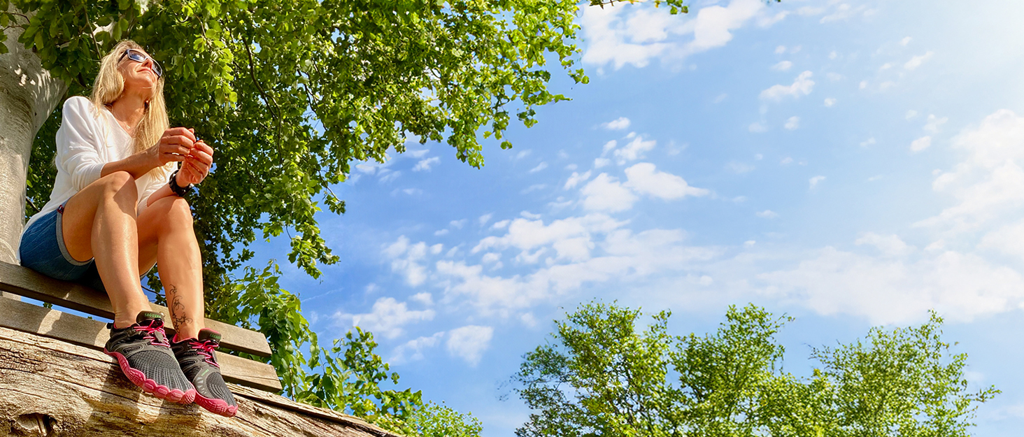 La escena de ocio al aire libre que muestra a alguien relajándose en una hamaca contra el cielo azul con árboles, parece estar en un entorno de campamento.
