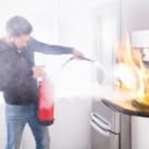 Man putting out a fire with extinguisher with residue and smoke in air