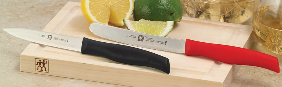 Two knives, a lime and a lemon on a wooden cutting board.