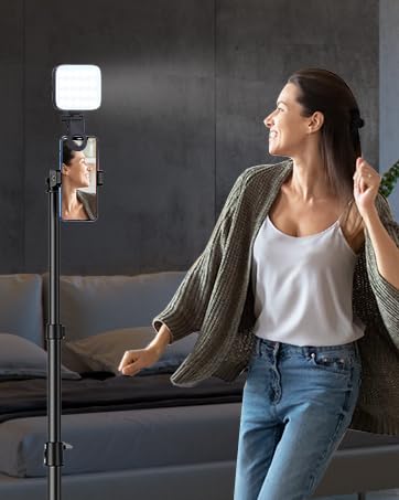 Woman using a square-shaped light device in a dark room, possibly for video or photography lighting purposes.
