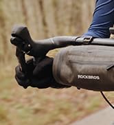 Gloved hands holding and demonstrating the use of specialized tactical or protective gloves in outdoor setting.