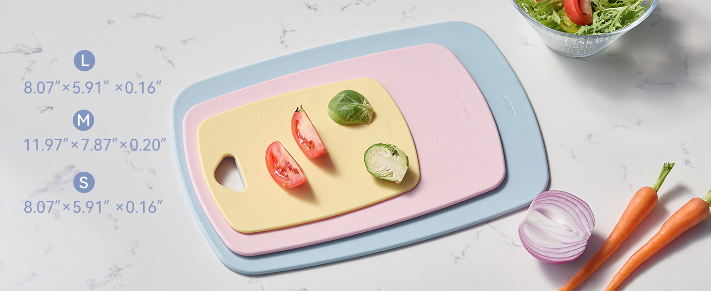 Three pastel cutting boards with tomato, Brussels sprouts, carrots, onion, and salad.