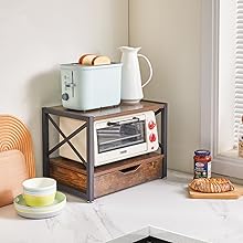 avec étagère à deux niveaux pouvant contenir un grille-pain, un pichet et un four grille-pain. Les articles environnants comprennent de la vaisselle, du pain et une chaise orange.