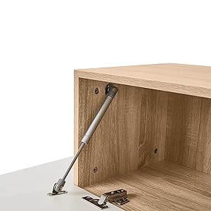 Ein Holzschrankinterieur mit einer silbernen Gasfederstütze, die an der Oberseite befestigt ist. Metallscharniere und Befestigungsmaterial sind auf der Unterseite sichtbar