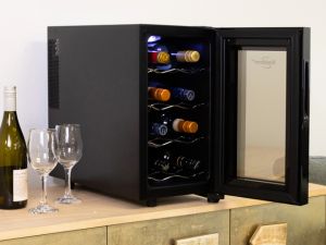 Black compact wine fridge on an elegant gold sideboard with a wine bottle and two glasses beside it