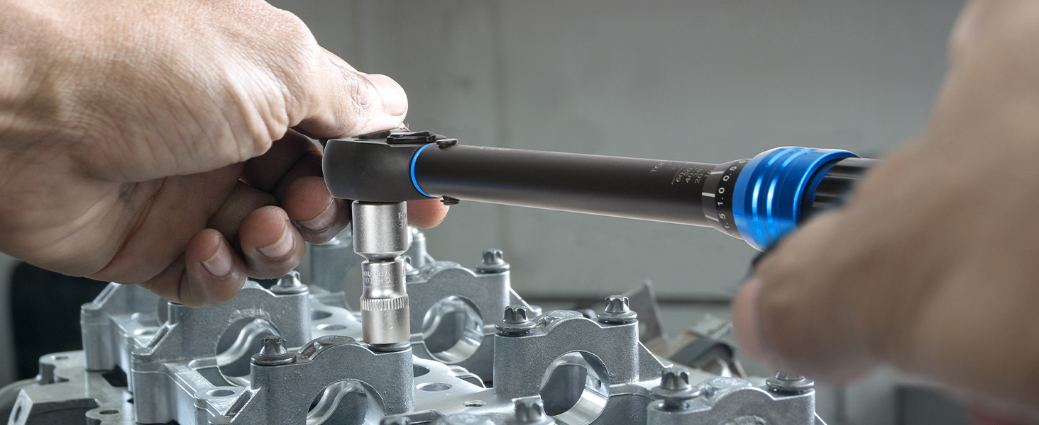 Close-up of hands using tools on a metallic mechanical component, with a blue attachment visible on the tool end.