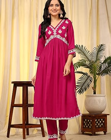 Full-length magenta dress with intricate white embroidery detail, featuring three-quarter sleeves and matching pants, displayed against beige curtain backdrop.