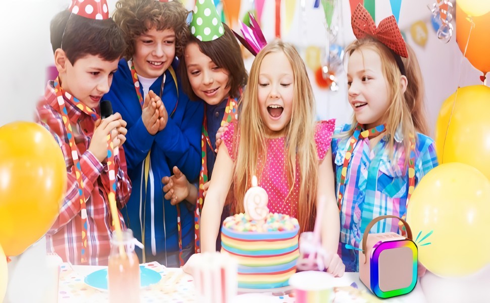 Group of kids celebrating birthday with cake and colorful karaoke mic speaker on the table