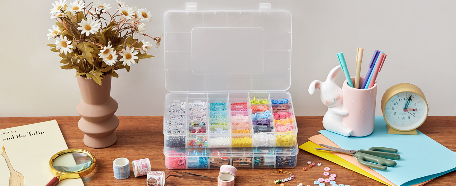 Organizer-Set für Bastelbedarf auf Holzoberfläche Durchsichtige Plastikbox mit Fächern, die mit bunten Perlen gefüllt sind. Zu den Gegenständen in der Umgebung gehören Blumen, Stifte und