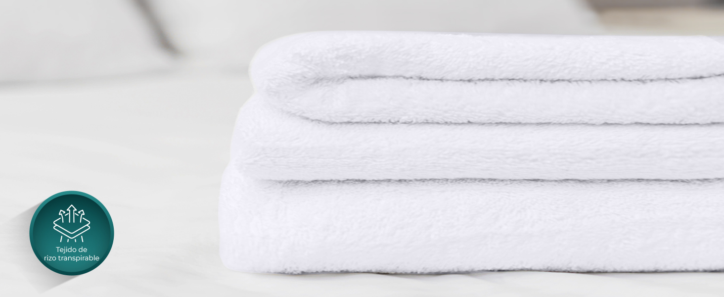 Pila de toalhas brancas dobradas com um pequeno logotipo circular verde ou uma etiqueta visível na esquina.