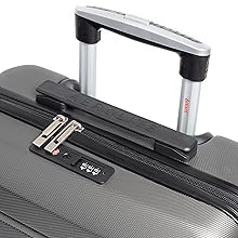 Primo piano della maniglia e del meccanismo di chiusura di una valigia. Presenta una maniglia telescopica, una serratura a combinazione e maniglie con cerniera su una superficie ruvida grigia della valigia