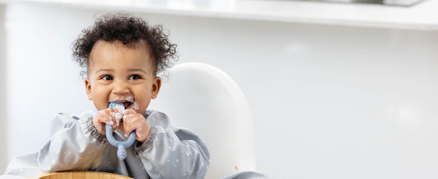 smiling baby in highchair weaing Coverall Weaning Bib