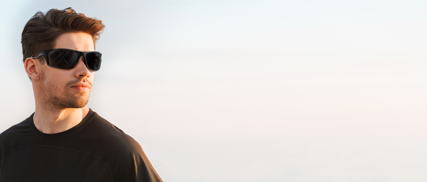 A person wearing black rectangular sunglasses with a sleek, modern design. The sunglasses have wide frames and dark lenses, providing full eye coverage.