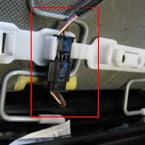 Primer plano de los componentes de la conexión eléctrica que muestra unidades de carcasa de plástico blanco con un cable azul visible en el soporte de montaje central