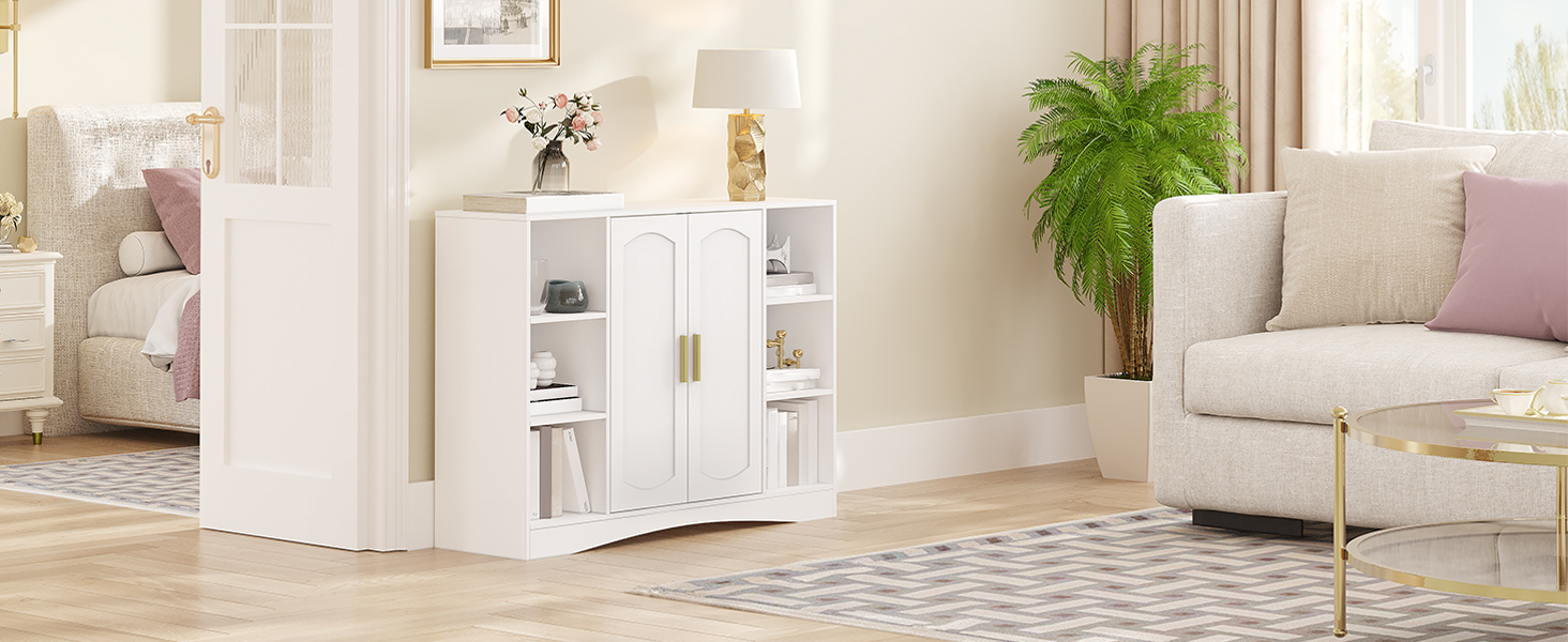 Weißer Aufbewahrungsschrank aus Holz mit Glastüren, offenen Regalen und goldenen Griffen. An einer Wand in einem hellen Wohnzimmer mit beigen Möbeln und einer Topfpflanze platziert