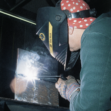 A welder works his torch on a piece of cast iron