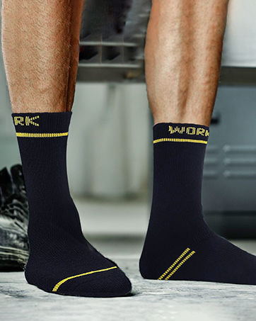 azul marino con rayas decorativas amarillas y detalles de texto, que se muestran usados en los pies contra el piso de concreto.