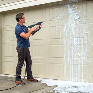 Person cleaning a garage door using a Kärcher high pressure washer and detergent