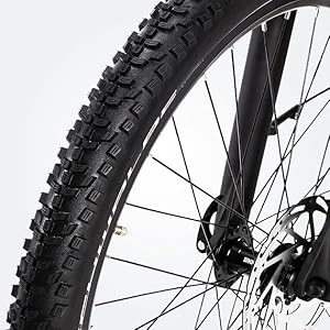 Nahaufnahme eines Mountainbike-Reifens mit aggressivem Stollenprofil, montiert auf einer schwarzen Felge.