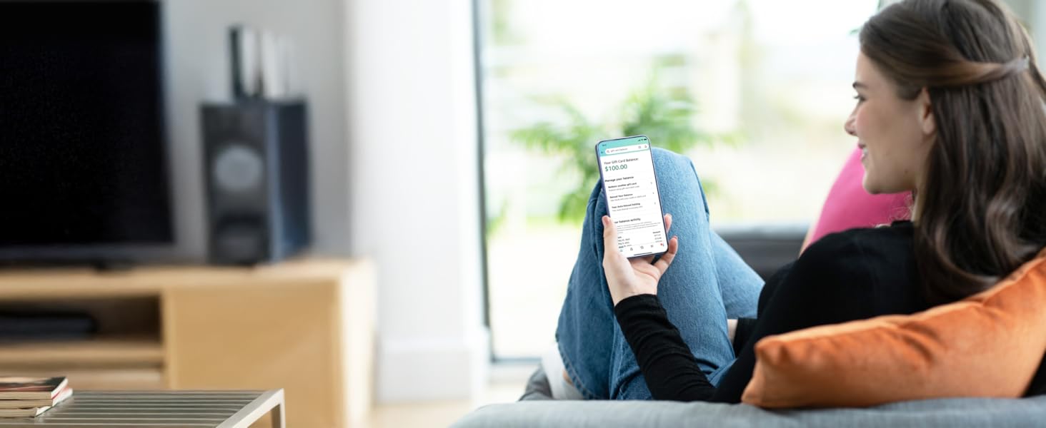 Person relaxing on couch while using a smartphone to manage Amazon Reload.
