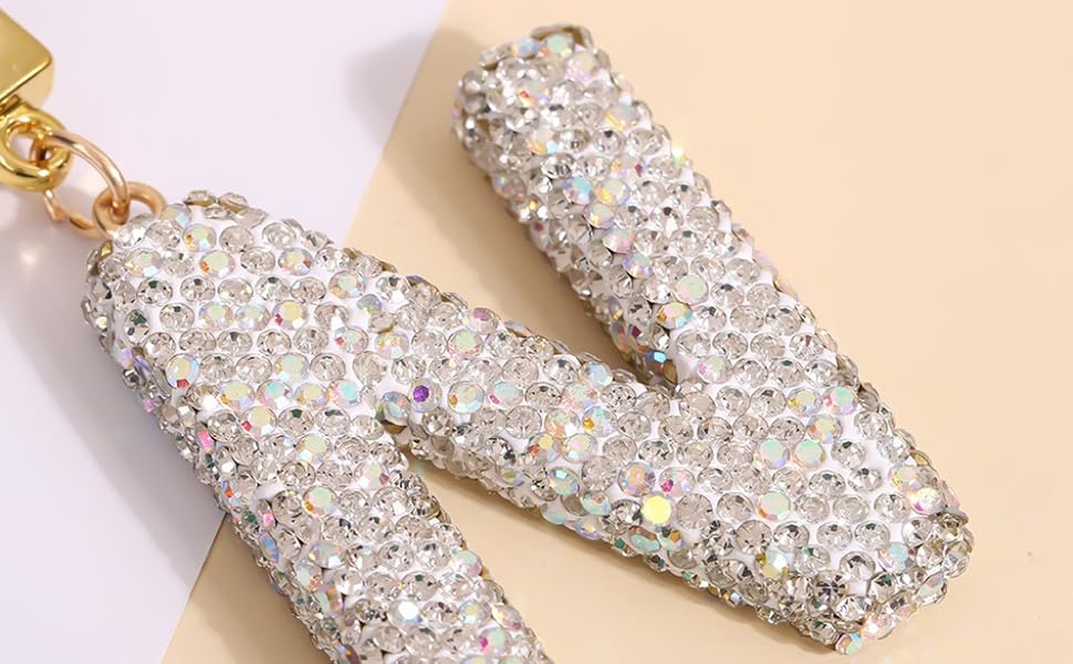 Immagini ravvicinate di unghie decorative con glitter argentati o decorazioni di strass su sfondo rosa.