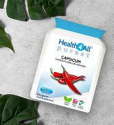White plastic bottle of HealthCall AJImoto supplement capsules. Label shows red chili pepper graphic. Bottle placed on white surface with green leaves in background.