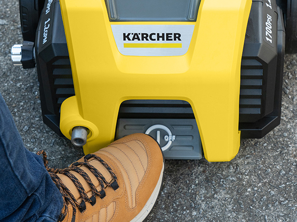 A close-up of a person stepping on the on/off foot switch of the K1700