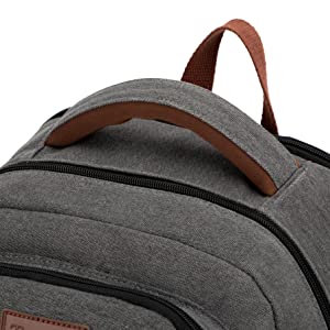 Vue rapprochée de la partie supérieure d'un sac à dos en toile gris foncé, doté d'une bandoulière en cuir marron et de multiples compartiments zippés