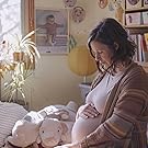 Pregnant woman gently cradling her baby bump in a nursery 
