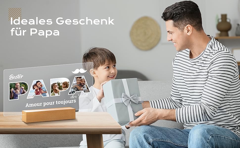 Wooden photo display with 'Ideales Geschenk für Papa' text. Shows multiple family photos on a stand. Gift being exchanged between adult and child.