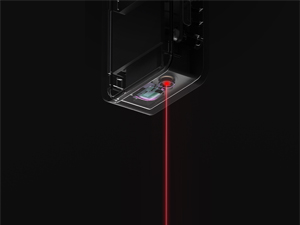 Primer plano de un dispositivo que emite un rayo láser rojo, escaneando un pequeño objeto rectangular, posiblemente un chip o una tarjeta
