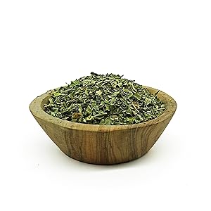 Bol en bois rempli d'herbes vertes séchées ou d'épices finement hachées, probablement un mélange d'assaisonnements culinaires.