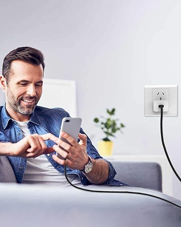 man plugging a phone into a wall outlet