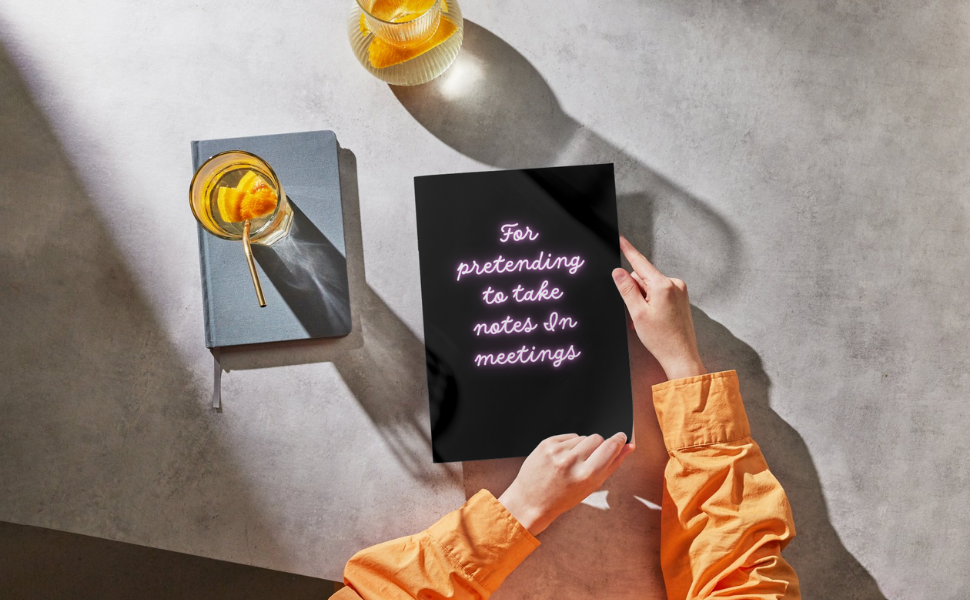 Woman paging through a black and neon coloured notebook on a grey tabletop