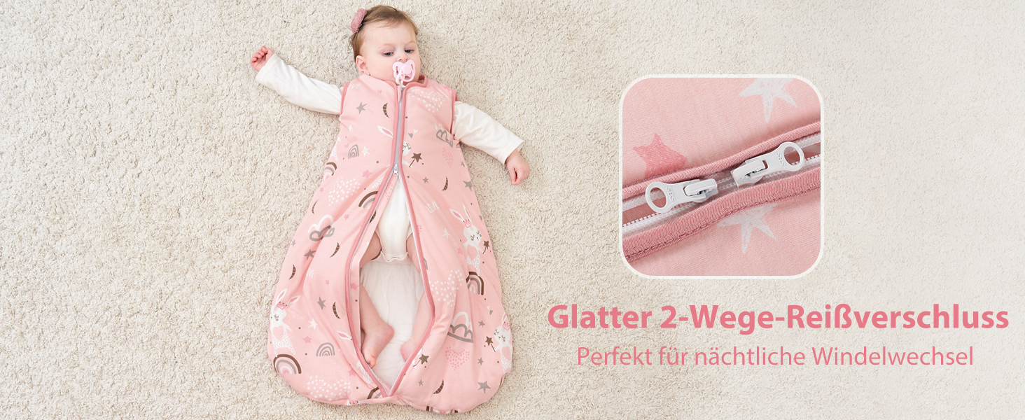 Rosafarbener Babyschlafsack mit einem darin schlafenden Kind. Die Nahaufnahme zeigt einen Zwei-Wege-Reißverschluss, der auf Deutsch als perfekt für einfaches Windelwechseln beschrieben