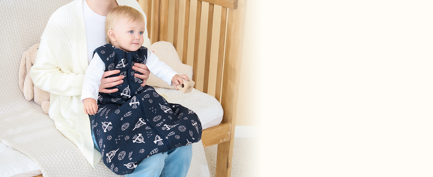 Schlafsack für Säuglinge mit blauem Blumenmuster auf Holzstuhl. Schlafsack in Babygröße mit langen Ärmeln und Reißverschluss für einfaches Windelwechseln