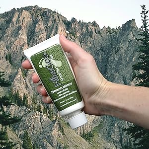 Hand holding a HikeGoo Tube 3 oz with mountain background
