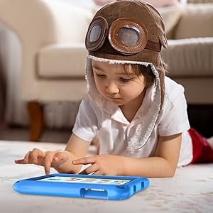 Child lying on floor using a blue tablet device protected by a durable rubber case, wearing brown aviator-style costume hat with goggles.