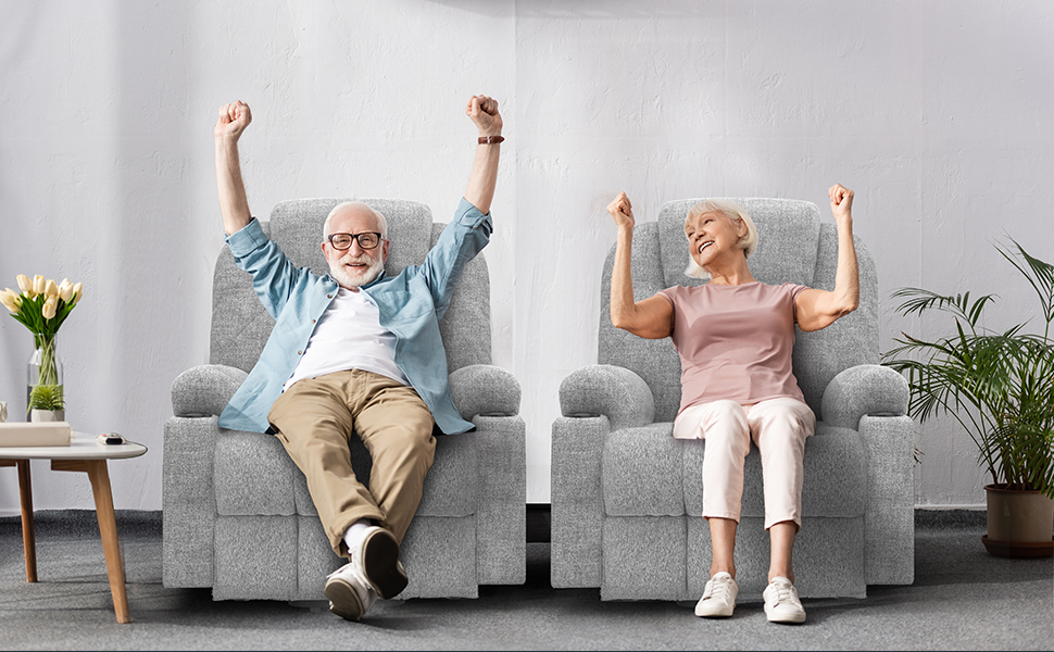 Zwei Personen, die in passenden grauen Liegen sitzen und freudig ihre Arme heben, mit sichtbarem Beistelltisch und Zimmerpflanzen