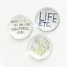 three clear round glass paperweights sit on a white counter