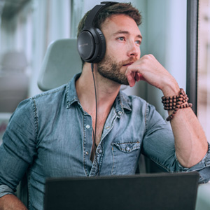 guy seated on a train, using his laptop with zen hybrid connected via aux in cable