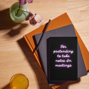 black and neon coloured notebook lying on top of a pile of stacked books