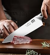Professional chef's knife cutting raw meat on wooden board. Large stainless steel blade with visible branding. Hands demonstrating precise cutting technique. Rosemary sprigs visible.