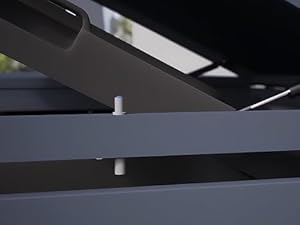 Nahaufnahme grauer Metallbauteile, möglicherweise Teil eines größeren Gerüsts oder Möbelstücks. Horizontale und abgewinkelte Balken kreuzen sich, wobei ein kleines weißes zylindrisches