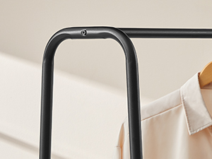 Fekete fémből készült fali ruhatartó vagy ruhaakasztó minimalista U-alakú dizájnnal bézs háttér előtt.