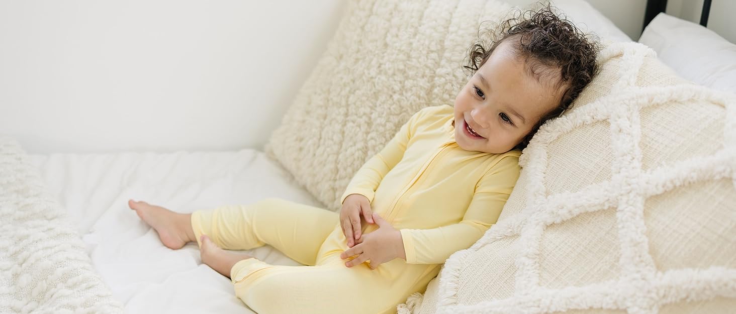 Toddler sitting on bed in Daffodil Romper